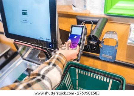 Customer completing a quick and convenient purchase using a purple credit card with nfc technology at an automated self service checkout terminal in a modern san francisco supermarket