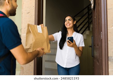 Customer delighted to receive a food delivery at home from a delivery person using a smartphone app - Powered by Shutterstock