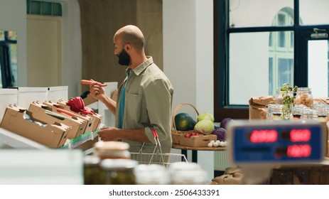 Customer examining fresh natural carrots on shelves at local zero waste store, looking to buy homegrown produce for sustainable lifestyle. Vegan man doing grocery shopping at ecological shop. - Powered by Shutterstock