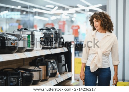 Customer examining a selection of multi cookers in a home appliance store, considering various options for modern kitchen convenience