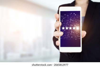 Customer Experience Concept. Hand Hold White Smartphone With Digital Hologram Five Stars Sign On Light Blurred Background. Review, Rating,Satisfaction.