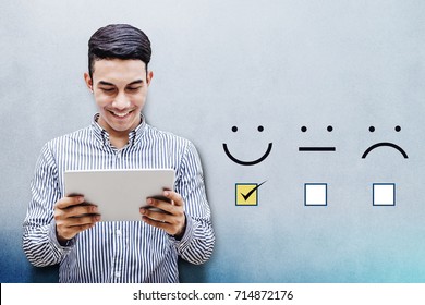Customer Experience Concept, Happy Businessman holding digital Tablet with a checked box on Excellent Smiley Face Rating for a Satisfaction Survey - Shutterstock ID 714872176