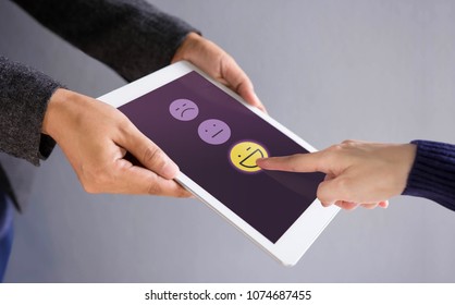 Customer Experience Concept. Happy Client Pressing A Smiley Face Sign On Digital Tablet For Online Satisfaction Survey