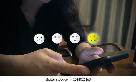 Customer experience concept. A customer using smartphone choose happy smile face icon. Depicts that customer is very satisfied.