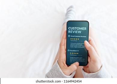 Customer Experience Concept. Woman Lying On Bed To Reading Online Review Via Smartphone Before Buying Products And Services, More Positive Feedback On Mobile Screen