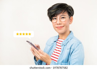 Customer Experience Ratings Concept. An Asian Woman Using A Smartphone To Submit Stars Feedback, And Review To Products Or Services She Quite Satisfied. Marketing Business Important Tools. Surveys.