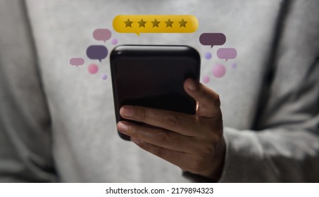 Customer Experiences Concept. Happy Client Using Smartphone To Submit Five Star Review Rating For Online Satisfaction Surveys. Positive Feedback On Mobile Phone