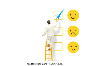 Customer Feedback Concept : Painter standing on ladder and painting blue tick checkbox on face emotions in happiness symbol for best service ranking.