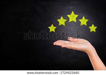 Customer Feedback, Experience and Satisfaction Concept : Hand showing and giving best service ranking with five stars on chalkboard.