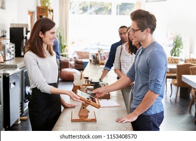 Customer At The Front Of The Queue Paying In A Coffee Shop