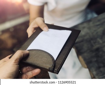 Customer Get Bill And Receipt From Waiter In Restaurant. Black Leather Tray With Receipt Bill. Service And Restaurant Catering Concept. Copy Space, Selective Focus