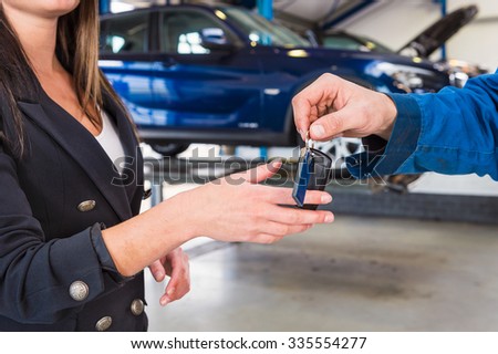 Customer gets the carkeys from mechanic after the maintanace of her vehicle