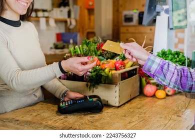 Customer girl paying for shopping at checkout in a grocery store - Young woman taking a credit card from a customer in a biologic market - Powered by Shutterstock