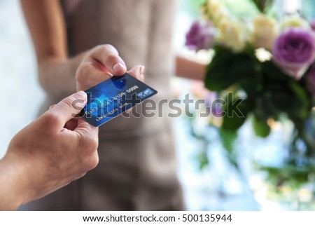Customer giving credit card to florist at flower shop, closeup