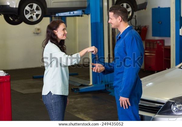 Customer giving her car keys to mechanic at the\
repair garage