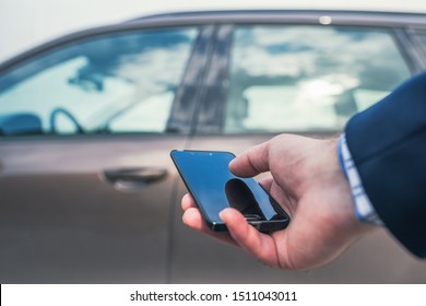 Customer hand holding mobile phone for opening car door. Car sharing service or rental concept.   
