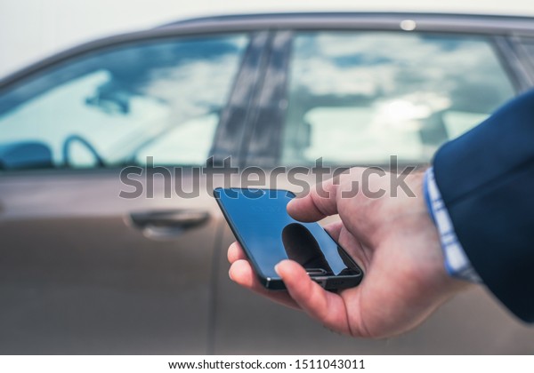 Customer hand holding mobile phone\
for opening car door. Car sharing service or rental concept.  \
