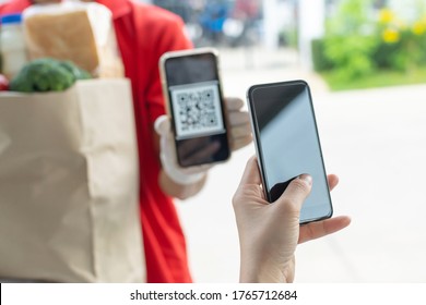 customer hand using digital mobile phone scan QR code paying for buying fresh food set bag from food delivery service man, express delivery, digital payment technology and fast food delivery concept