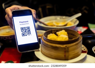 Customer hand using smart phone to scan QR code tag with blur dim sum or chinese food to accepted generate digital pay without money. Qr code payment concept.