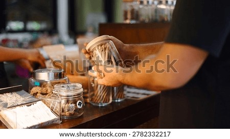 Customer hands selecting pre rolled cannabis joints in a modern dispensary shop