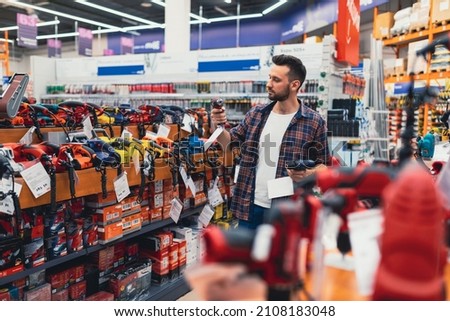 a customer in a hardware store compares two screwdrivers