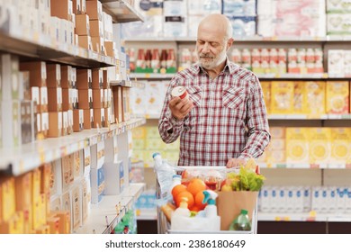 Customer holding a can and reading the product food label at the supermarket, grocery shopping concept - Powered by Shutterstock