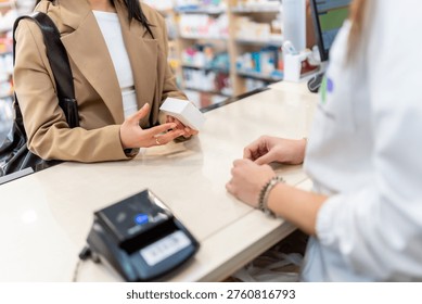 Customer holding a medication box while interacting with a pharmacist at the checkout counter in a drugstore, representing health care services, retail transactions, and medical advice