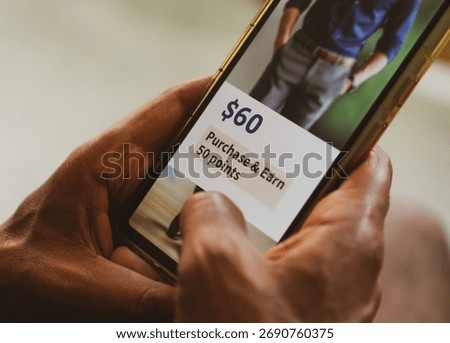 Customer loyalty program concept in e-commerce. Man holding phone displaying earning points after purchasing online.