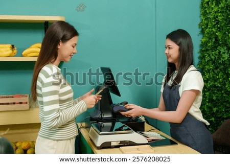 Customer making a contactless payment using a credit card in a small fruit shop. Highlights cashless transaction, modern technology, and the convenience of eco-friendly local businesses.
