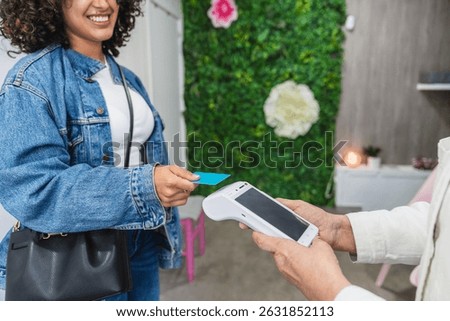 Customer making a contactless payment using credit card at a beauty center, holding the card close to the pos terminal