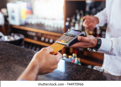 Customer making payment using credit card. Close up of card payment being made between customer and bartender in cafe. - Powered by Shutterstock