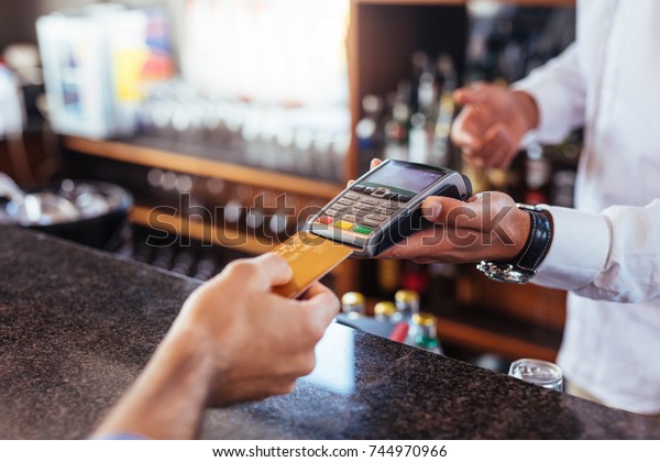 Customer
making payment using credit card. Close up of card payment being
made between customer and bartender in
cafe.