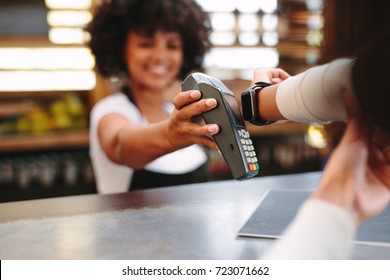 Customer making wireless or contactless payment using smartwatch. Store worker accepting payment over nfc technology.