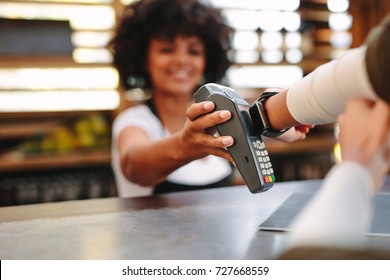 Customer making wireless or contactless payment using smartwatch. Cashier accepting payment over nfc technology. - Powered by Shutterstock