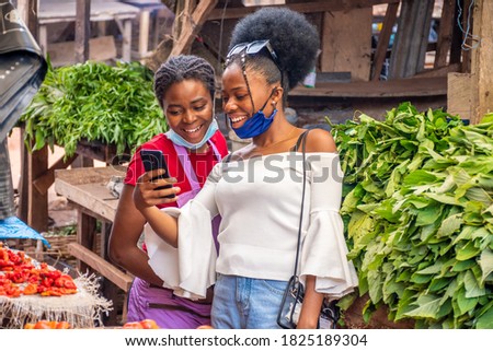 customer in a market showing a trader something exciting on her phone