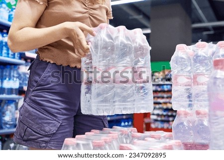 Customer with pack of water bottles in store