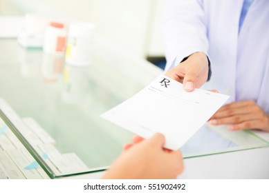 Customer (patient) giving prescription to pharmacist in pharmacy - Shutterstock ID 551902492