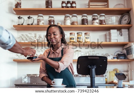 Customer paying a barista for a purchase in a cafe using a bank card and nfs technology 