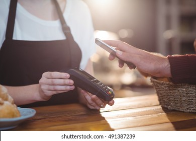 Customer paying bill through smartphone using NFC technology in cafe