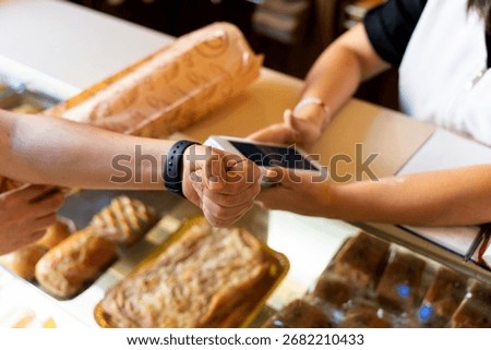 Customer paying for bread with smartwatch, using contactless mobile payment at a bakery or bread shop