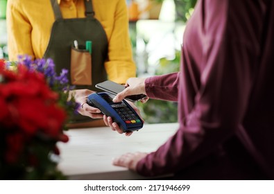 Customer paying in a flower shop using her smartphone, electronic payments concept