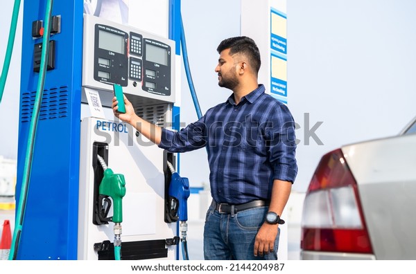 customer paying at\
pertrol bump by scanning QR code using mobile phone after refuling\
car - concept of digital contact less payment, wireless transaction\
and petroleum service