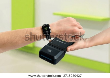 Customer paying with smart watch using contactless POS terminal indoors, demonstrating tap payment, wearable technology, digital transaction, and modern retail checkout process