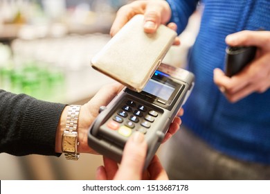 Customer pays contactlessly with smartphone via NFC on reader in retail - Shutterstock ID 1513687178