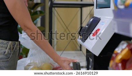 Customer pays at self-checkout using smartphone next to grocery bag. High quality photo
