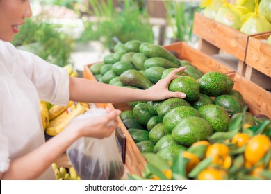 Customer Picking Up Avocadoes At The Grocery Store