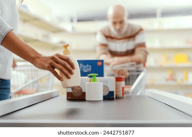 Customer placing groceries on the supermarket checkout conveyor belt, hands close up