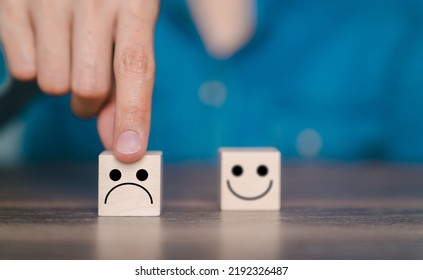 The Customer Pointed His Finger At The Frown Icon On The Wooden Block. Customer Satisfaction Evaluation Concept, Bad Experience, Bad Review, Low Score, Not Satisfied.