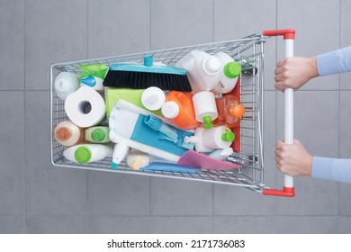 Customer pushing a shopping cart full of cleaning products and housekeeping equipment, top view