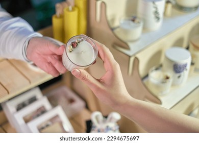 customer receives a unique, handcrafted candle from a dedicated craftswoman, amidst a lively marketplace teeming with handcrafted candles and other locally made items - Powered by Shutterstock